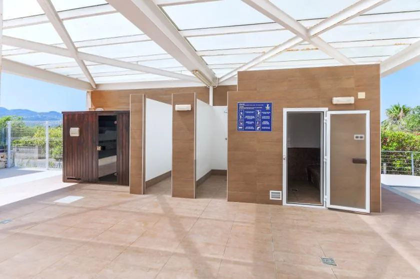 A covered outdoor restroom area with several doors and open views of greenery.