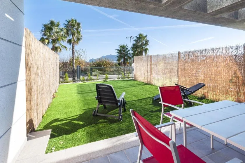 A patio with green lawn, outdoor seating, and a dining table.
