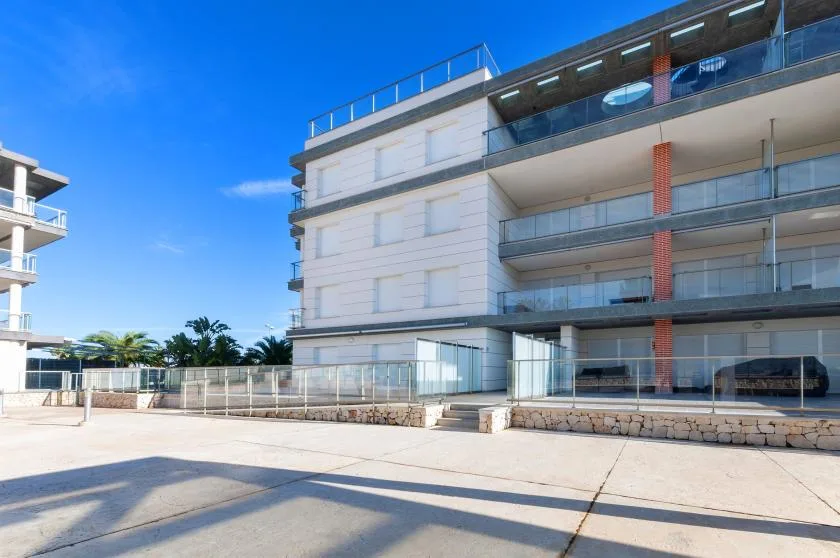 A modern apartment building with balconies faces a broad paved courtyard.