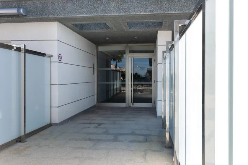 A covered building entrance corridor with glass doors at the far end.