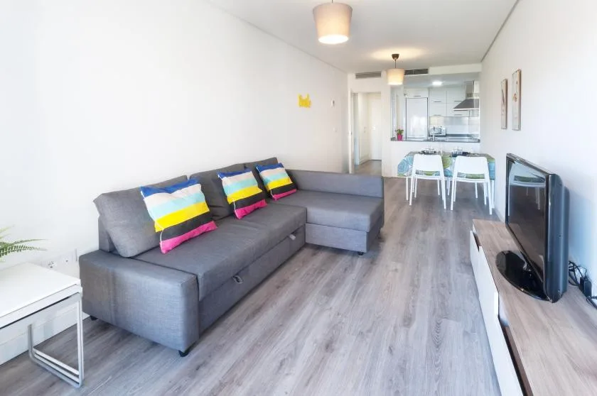 A bright living room with gray seating and a dining area beyond.