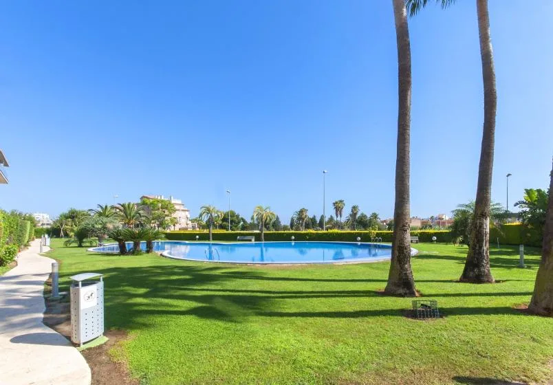 A landscaped outdoor pool area with a paved path and palm trees.