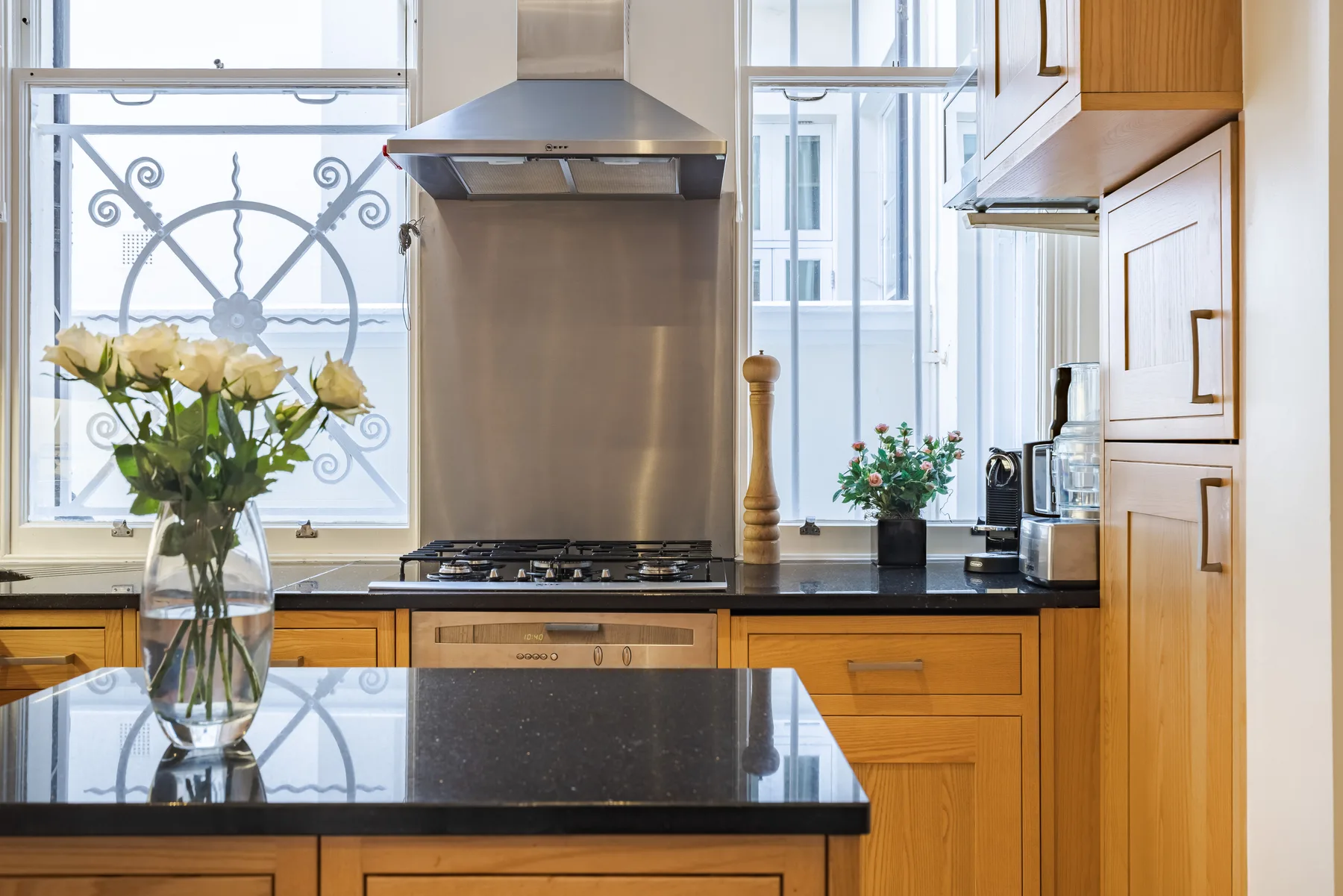 A bright kitchen with wooden cabinets, a cooktop, and a large window.