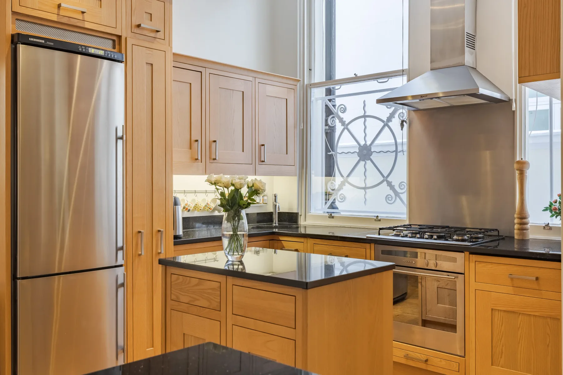 A bright kitchen with wood cabinetry, a central island, and stainless steel appliances.
