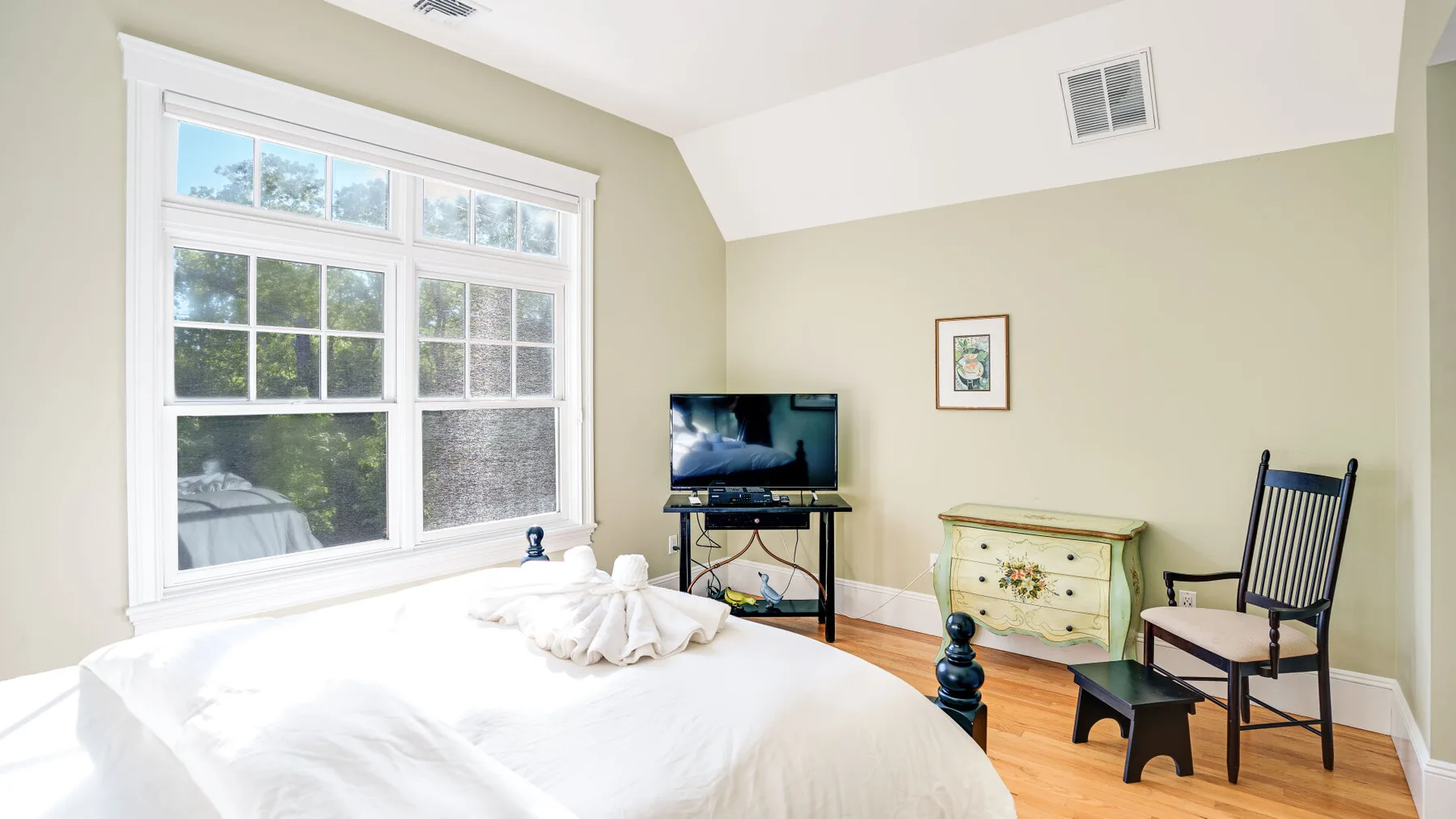 Un dormitorio con una cama grande, un televisor y una cómoda colorida.