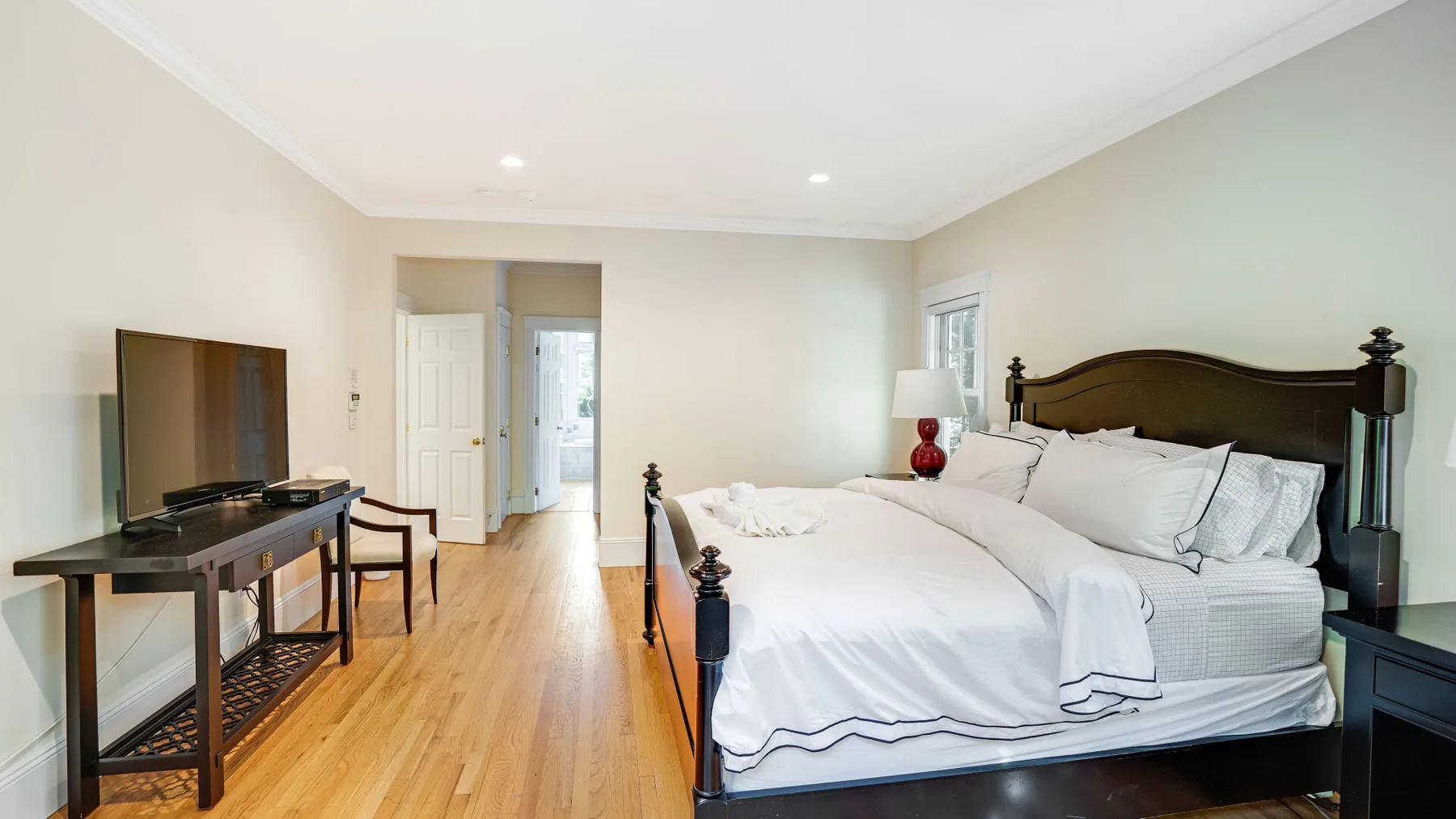 Un dormitorio con una cama grande, un escritorio pequeño y suelo de madera clara.