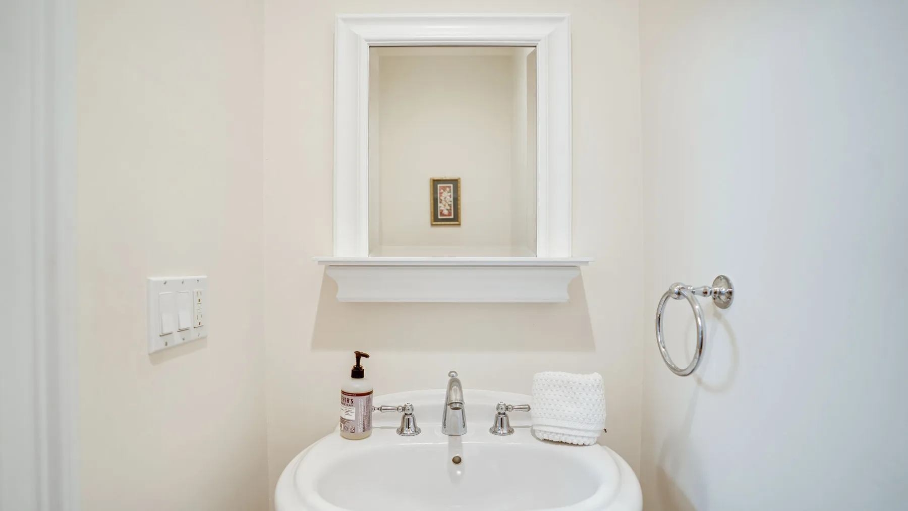 Un lavabo de baño con espejo y un aro para toalla en la pared.