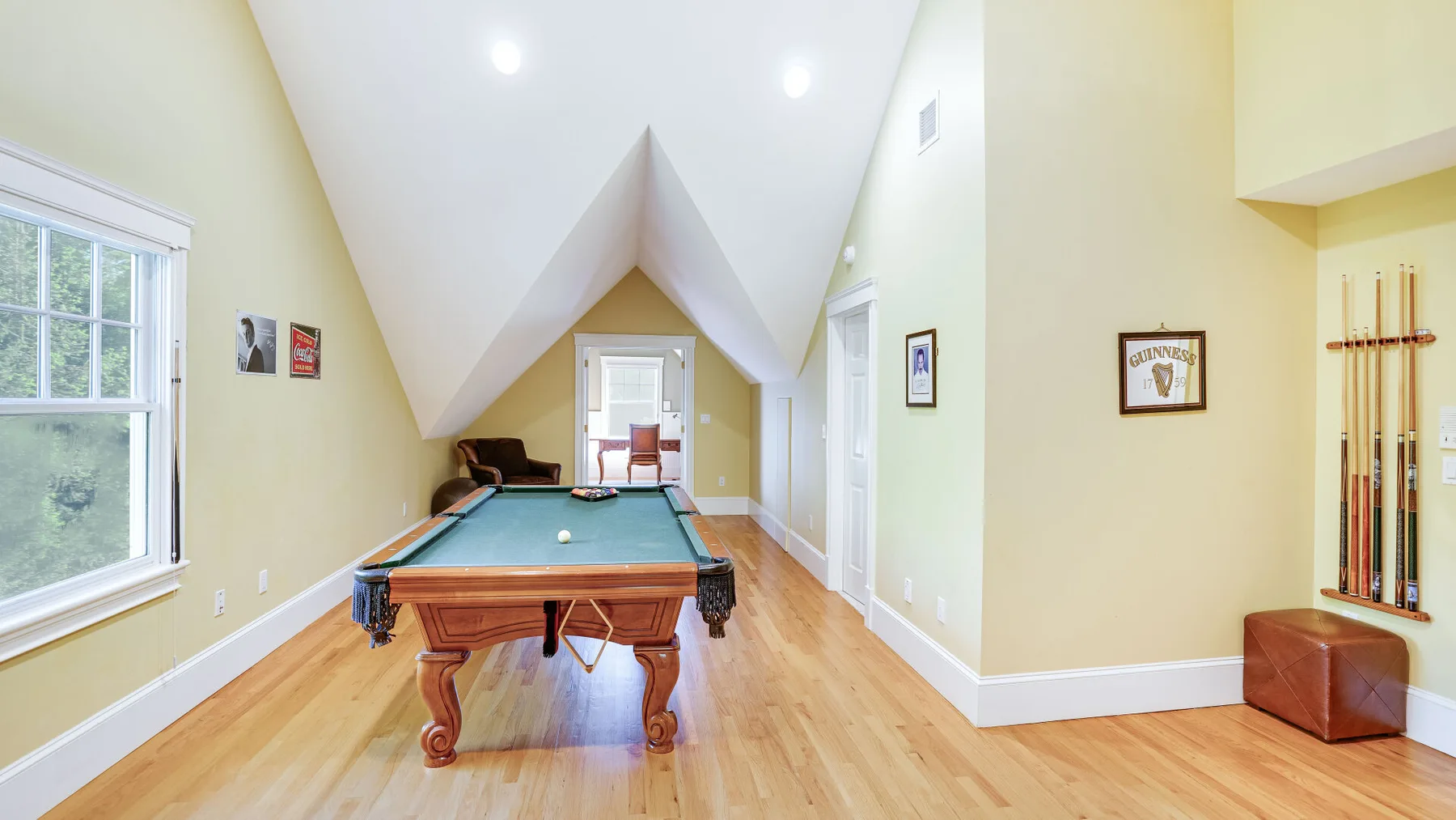 Una luminosa sala de juegos con una mesa de billar y tacos en la pared.