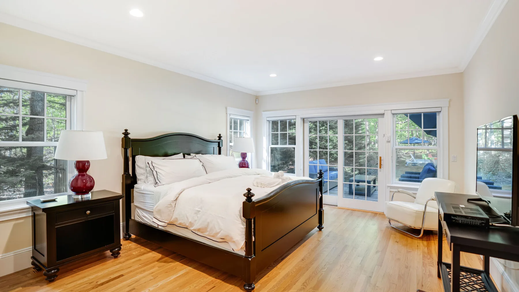 Un dormitorio luminoso con una cama grande, ventanas y puertas corredizas de vidrio.