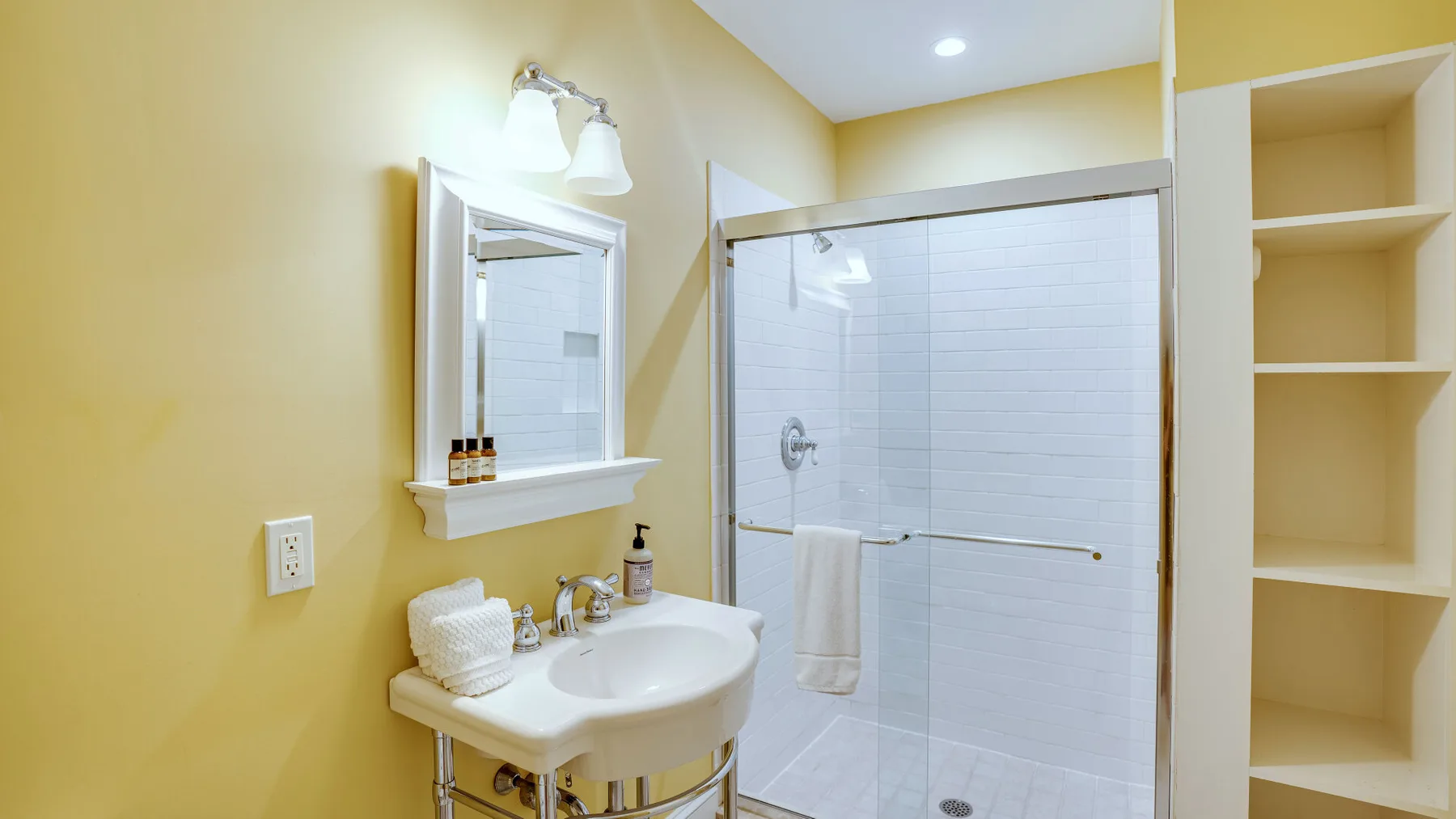 Un baño con lavabo, espejo y ducha con mampara de vidrio.