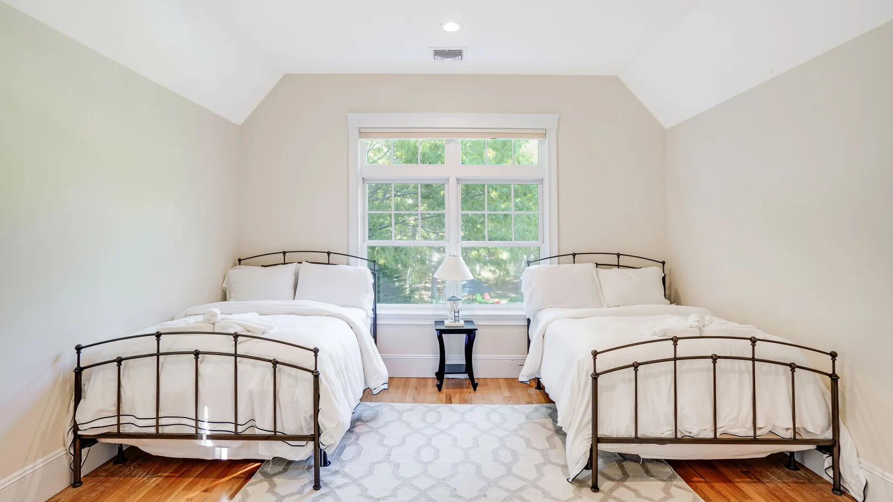 Un dormitorio luminoso con dos camas junto a una ventana grande.