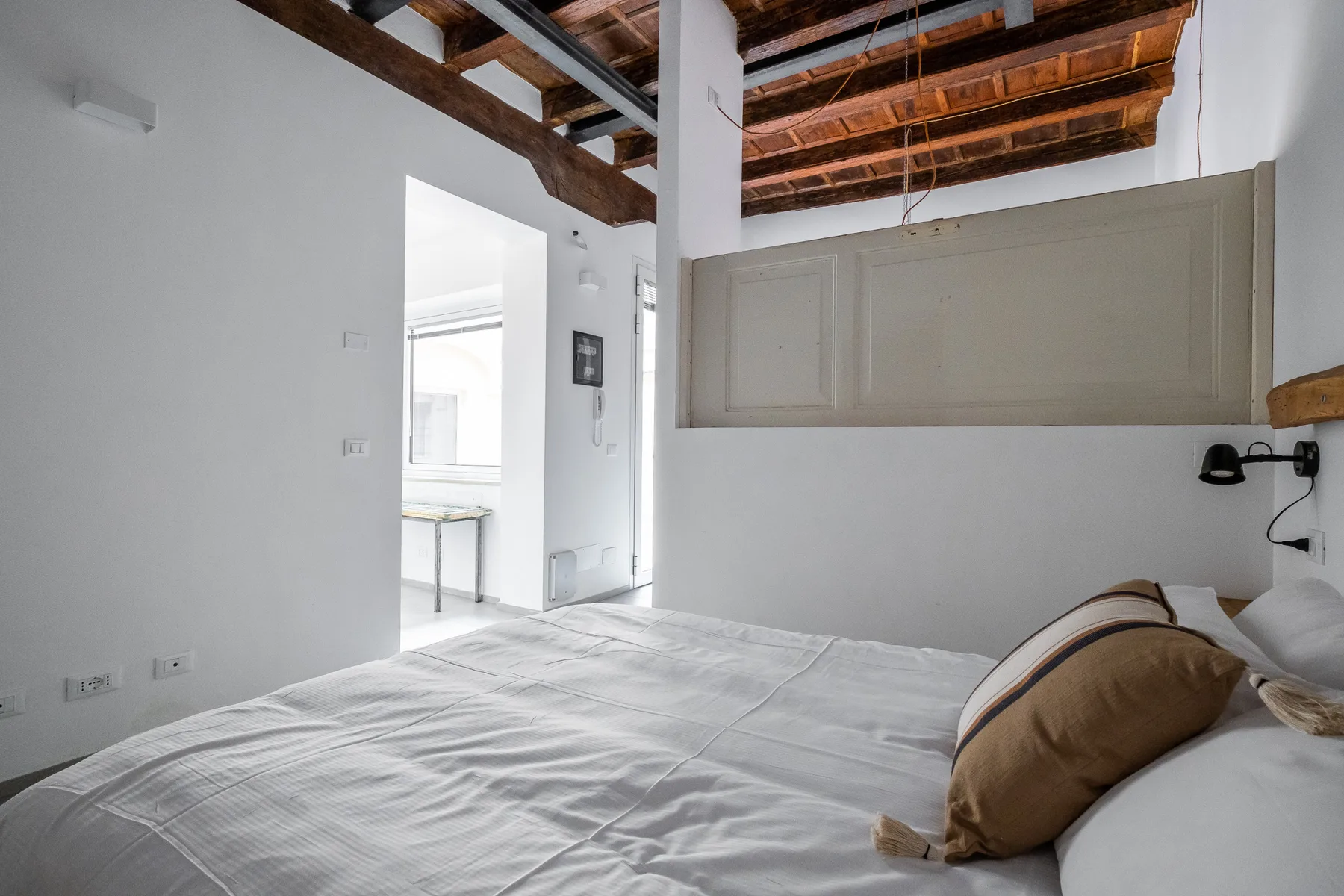 Bedroom with a bed beneath exposed wooden ceiling beams.