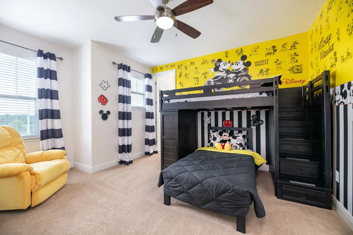 Un dormitorio temático de Mickey Mouse con una litera oscura y decoración amarilla en la pared.