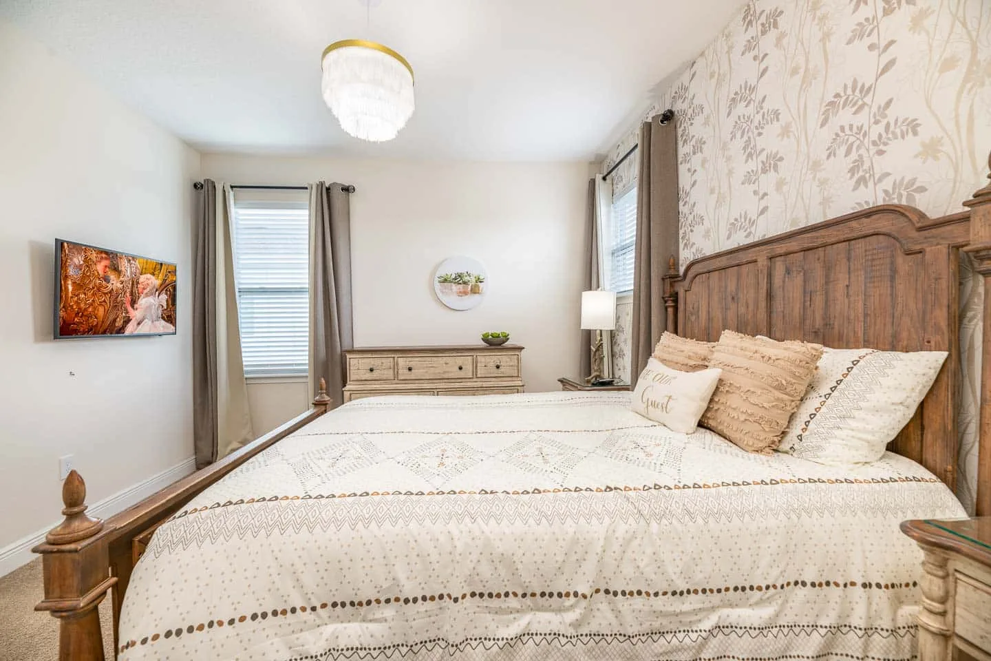 Un dormitorio con una cama grande, ropa de cama estampada y ventanas con persianas.