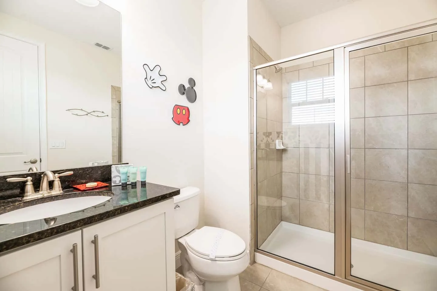 Un baño luminoso con lavabo, inodoro y ducha de cristal.