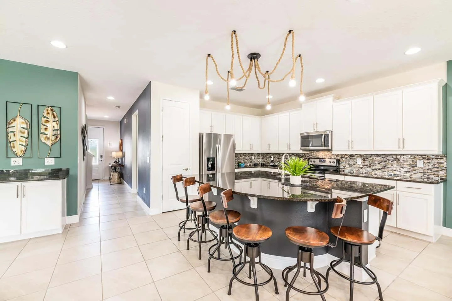 Una cocina luminosa con una isla grande, asientos y gabinetes blancos.