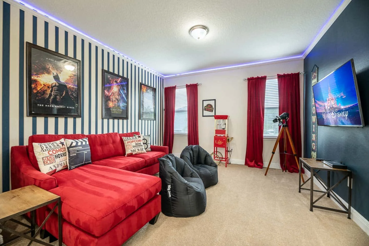 A colorful living room with red seating, framed posters, and a television.