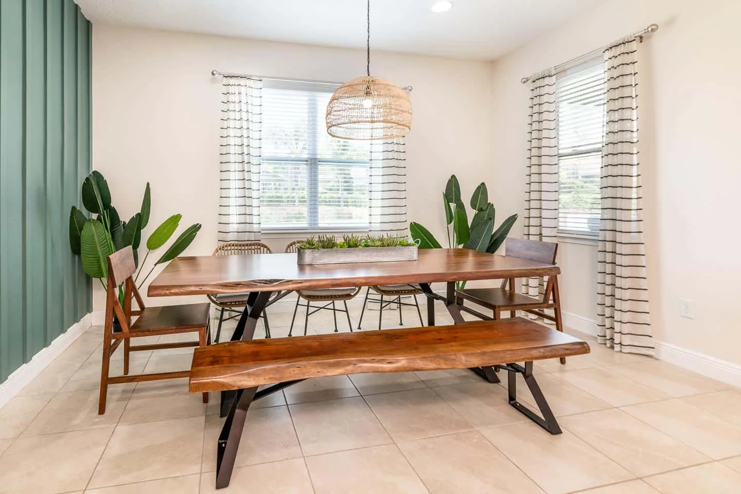 Un comedor con una mesa de madera, bancos y ventanas grandes.