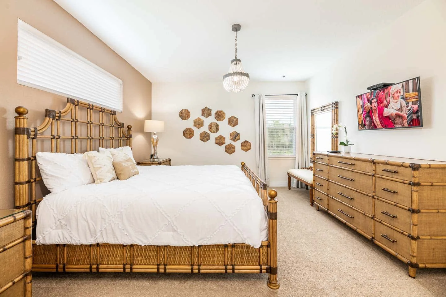 Un dormitorio luminoso cuenta con una cama grande, una cómoda y un televisor.