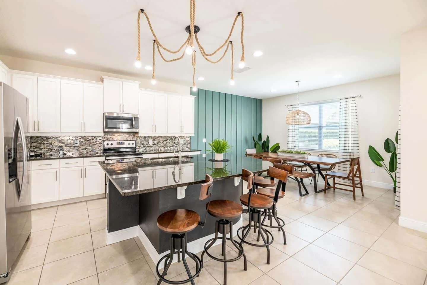 Una cocina y comedor luminosos con una isla central y una mesa junto a la ventana.