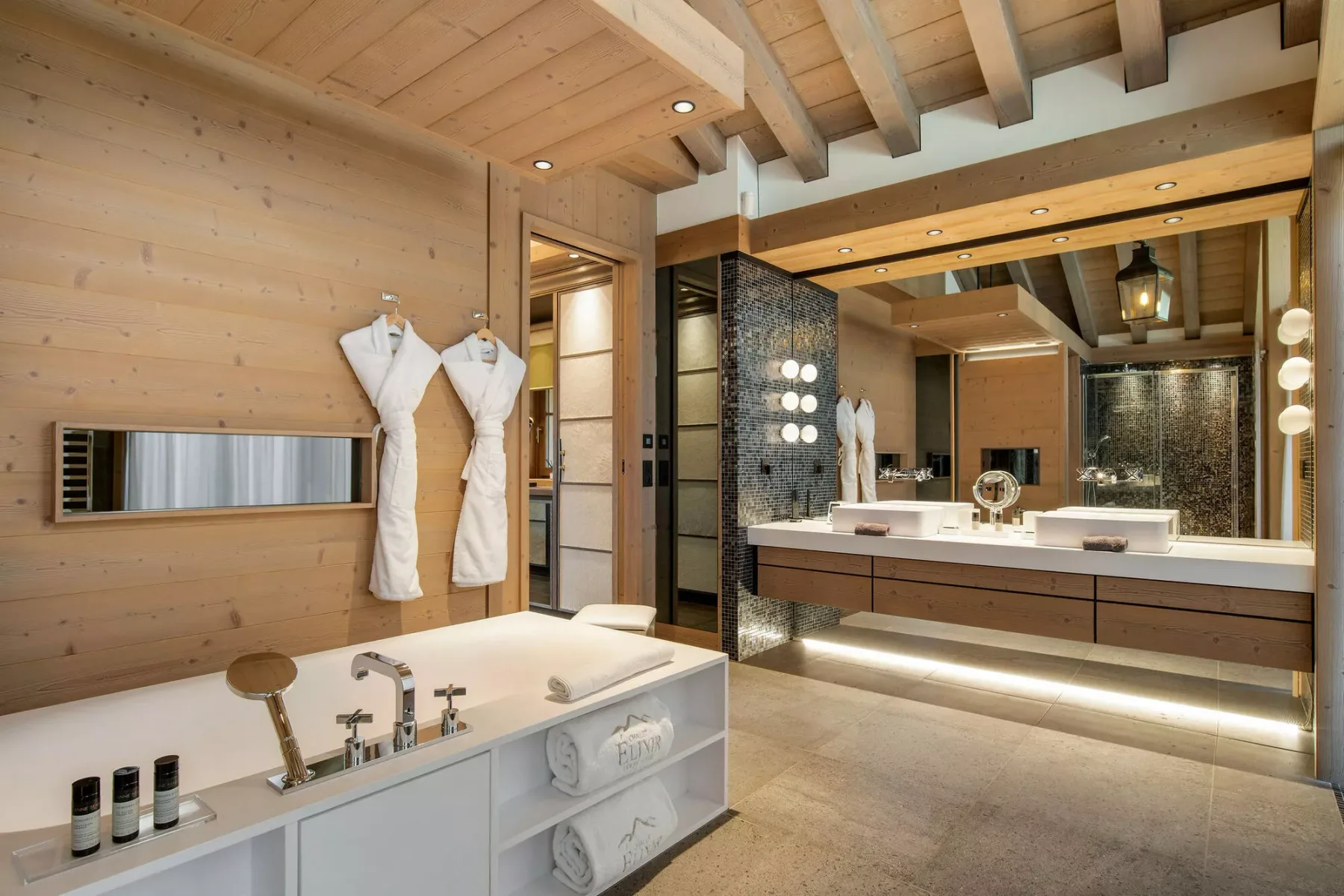 Un baño amplio con una bañera exenta y un largo tocador bajo vigas expuestas.