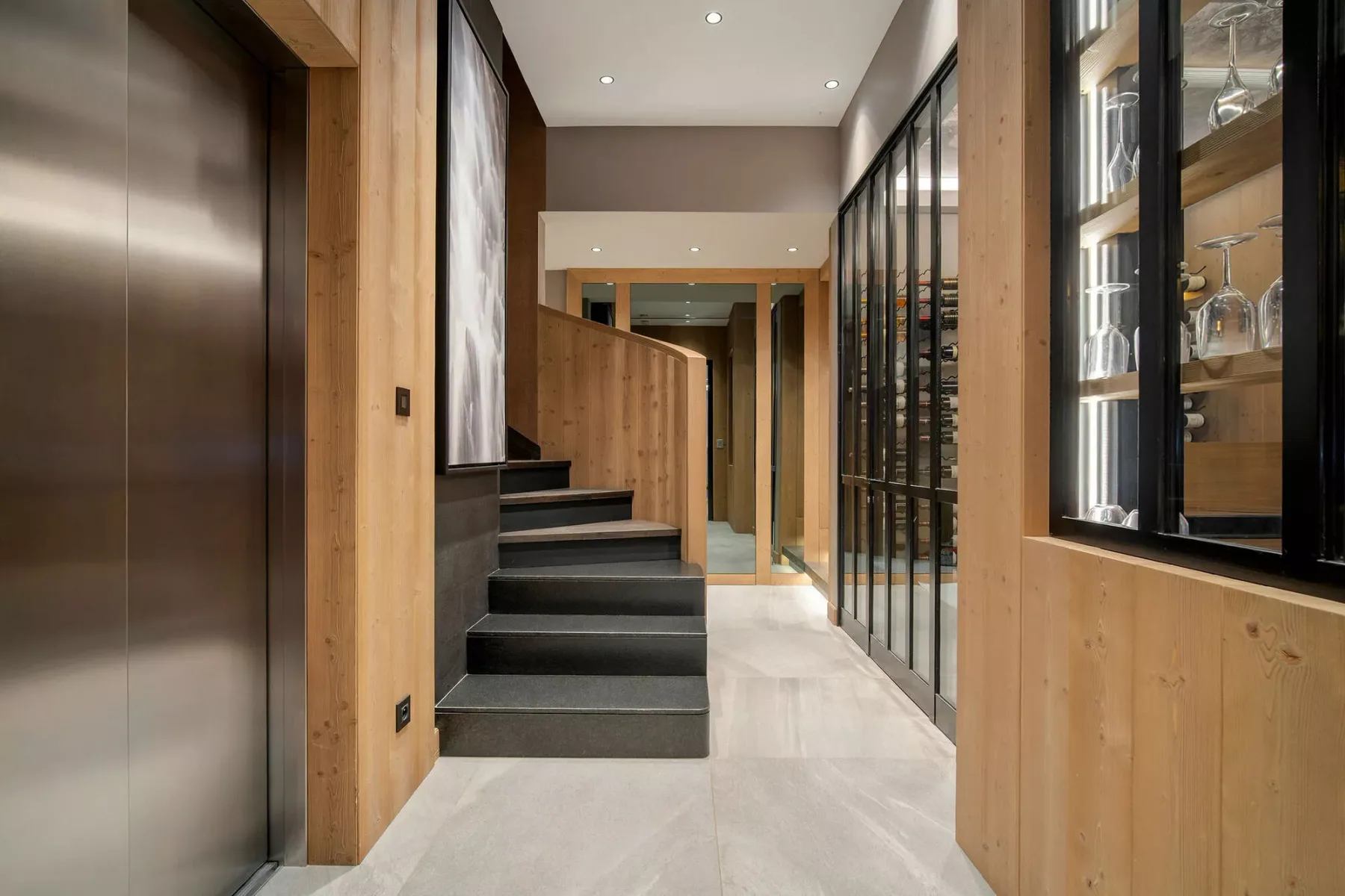 Un pasillo interior moderno con una escalera corta y vitrinas con puertas de vidrio.