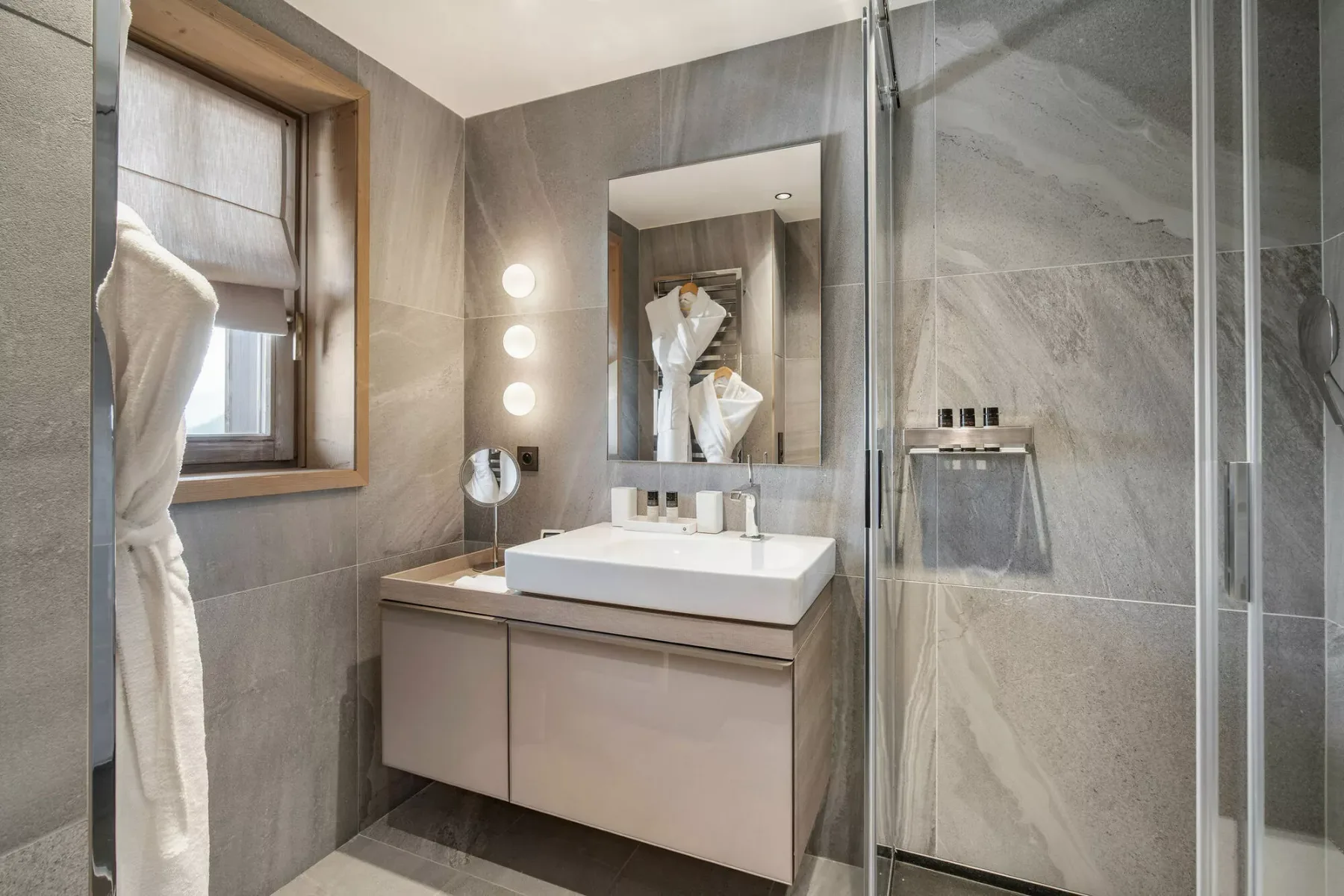 Baño moderno con lavabo, espejo y ducha de cristal.