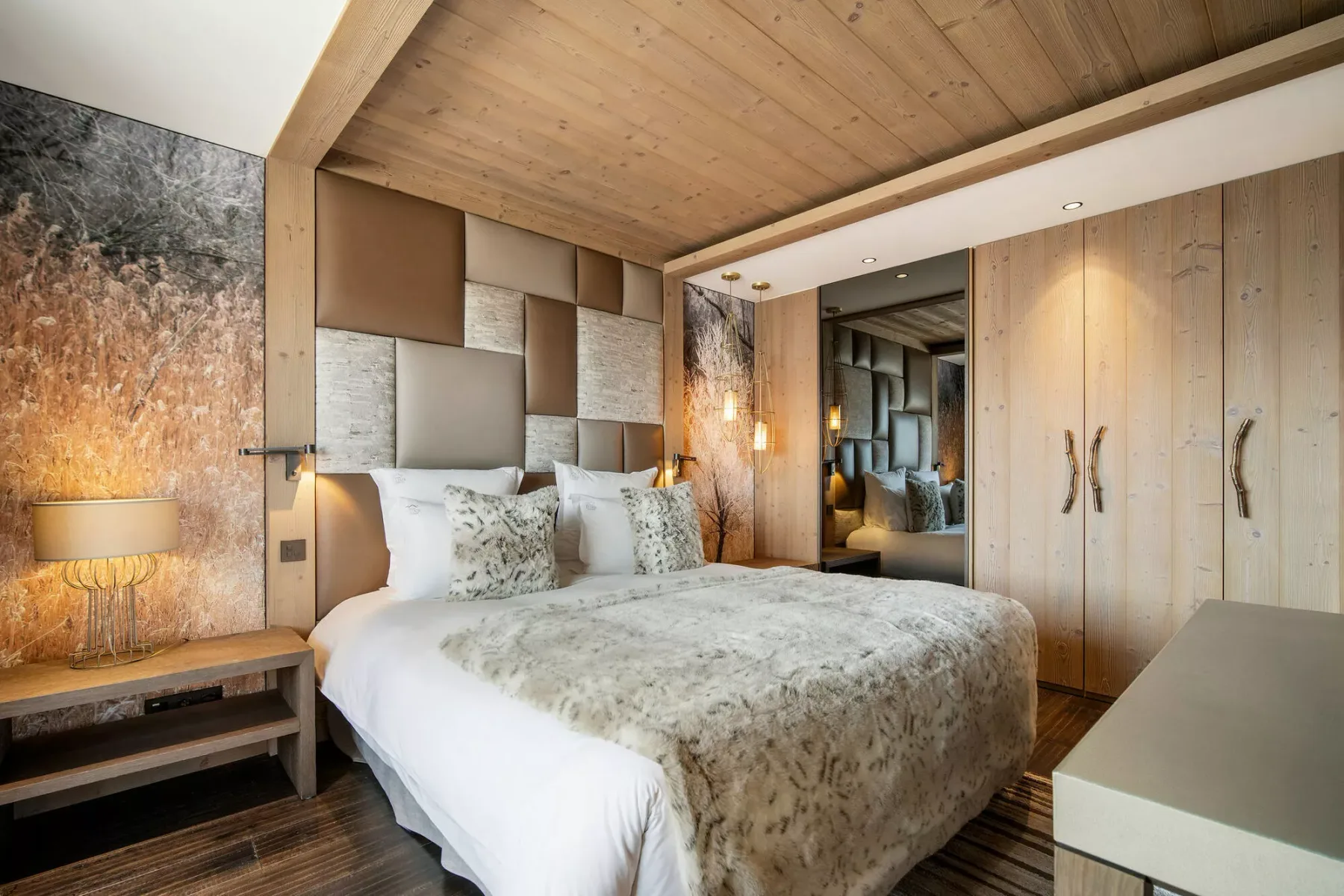 Un dormitorio con una cama bajo un techo de madera y junto a armarios empotrados.