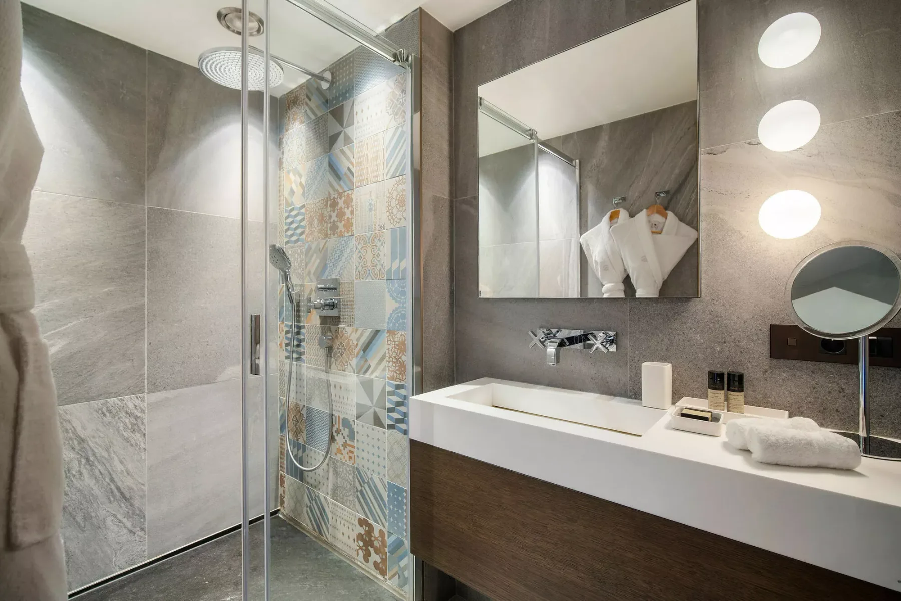 Un baño moderno con una ducha de vidrio y un amplio tocador bajo un espejo.