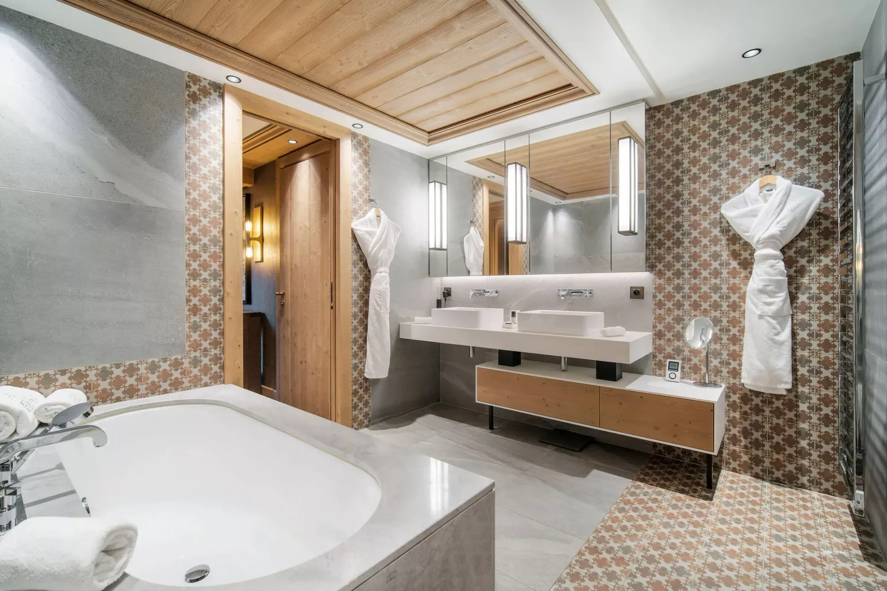 Un baño revestido de azulejos con bañera, lavabo doble y espejo.
