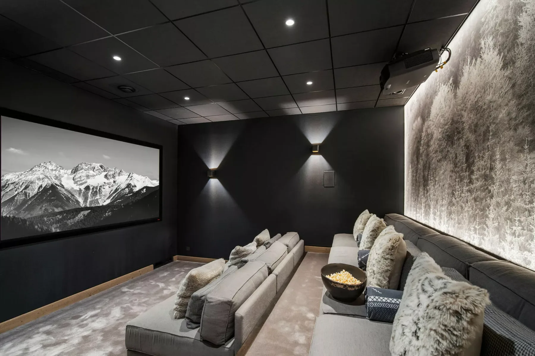 Un cine en casa oscuro con una pantalla grande y asientos acolchados.
