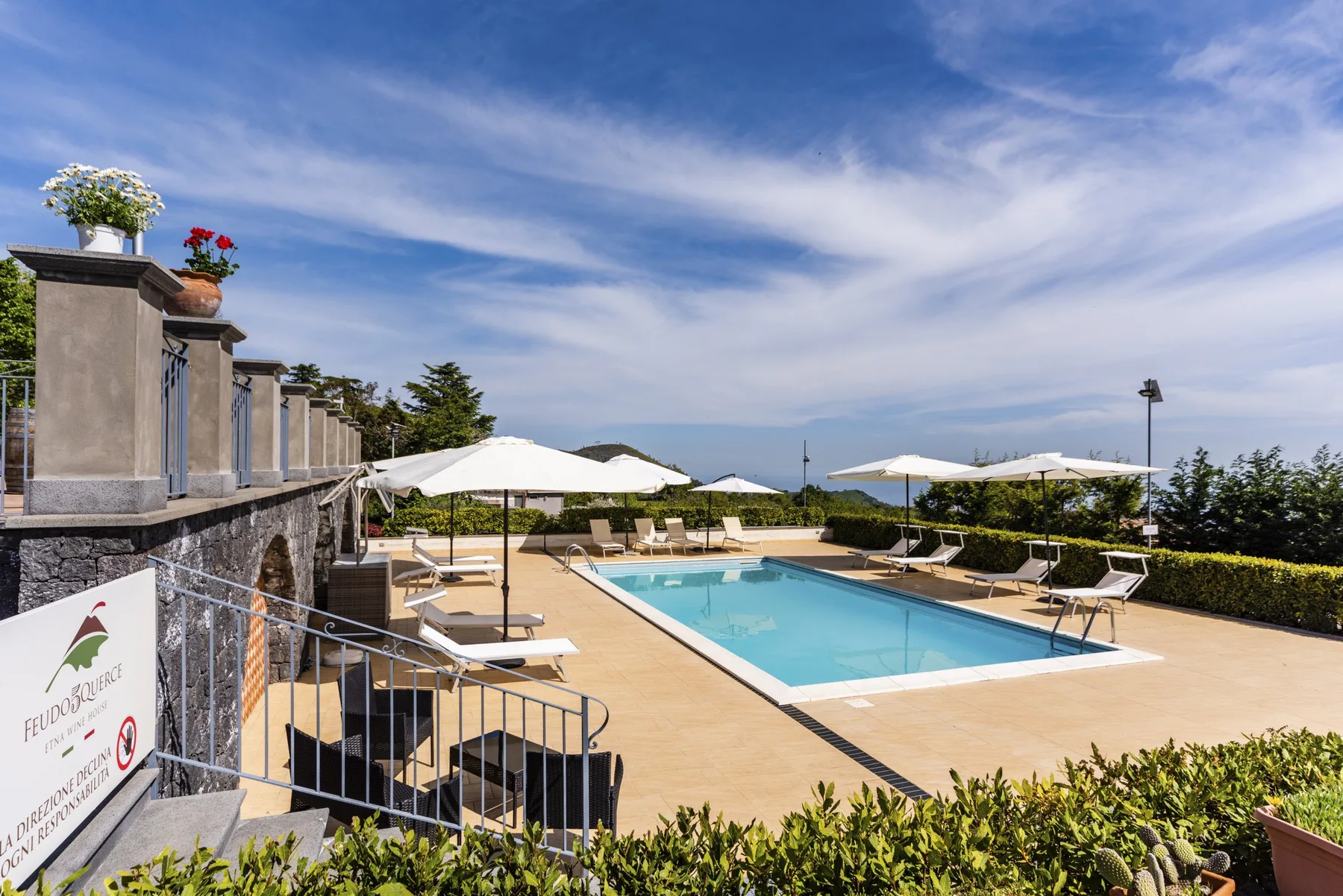 Una piscina al aire libre está rodeada de asientos para descansar y sombrillas abiertas.
