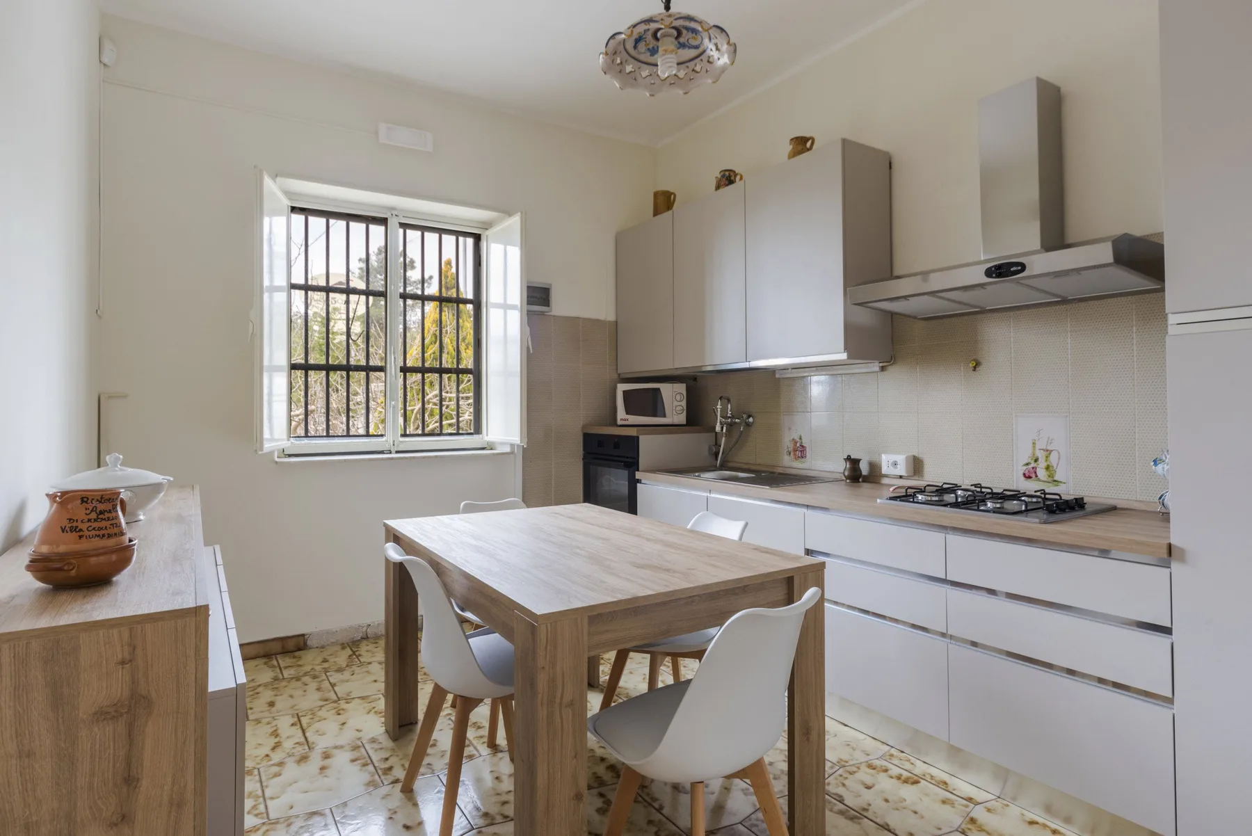 Una cocina luminosa con una mesa de comedor de madera y armarios blancos.