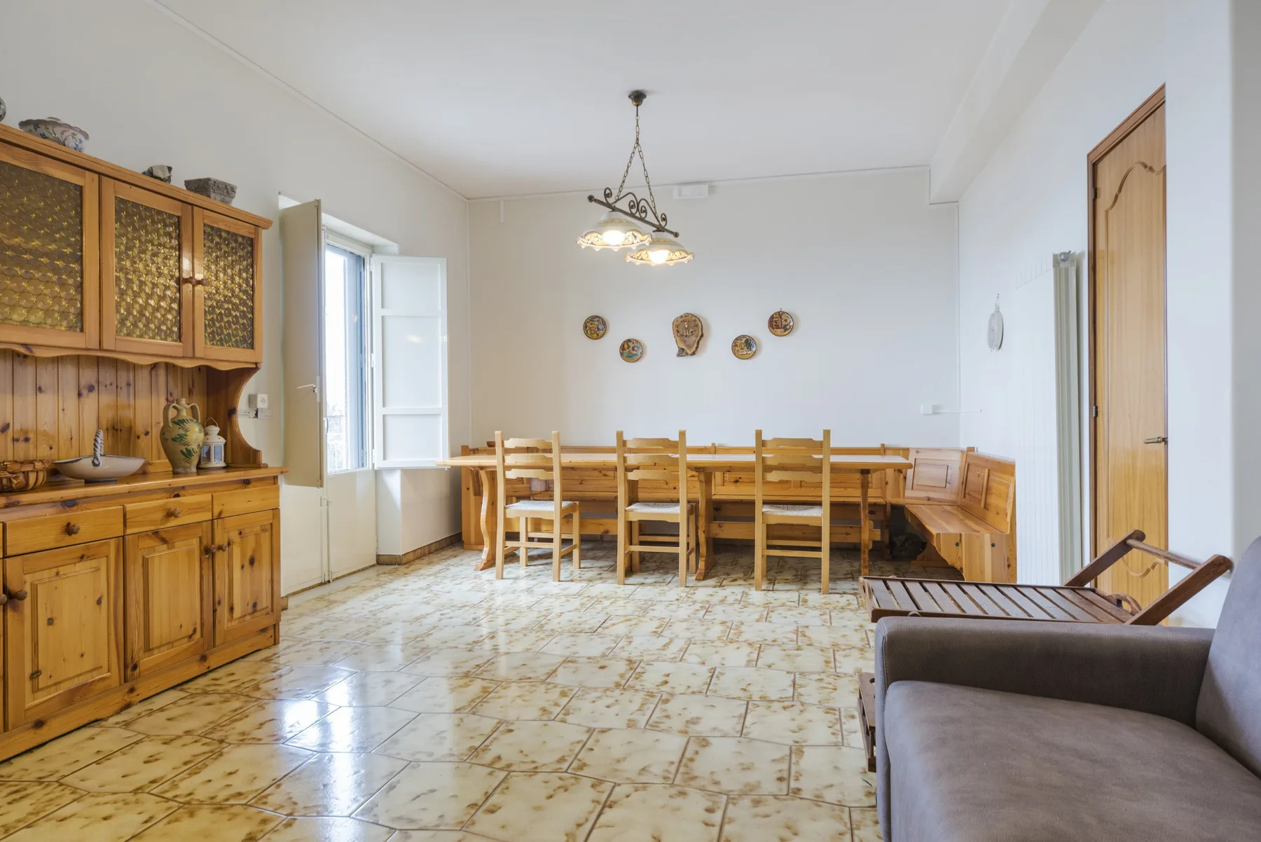 Un comedor con una mesa larga de madera y sillas junto a un gran armario.