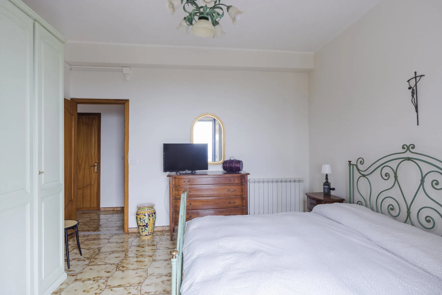 Un dormitorio con una cama, una cómoda de madera y un televisor.