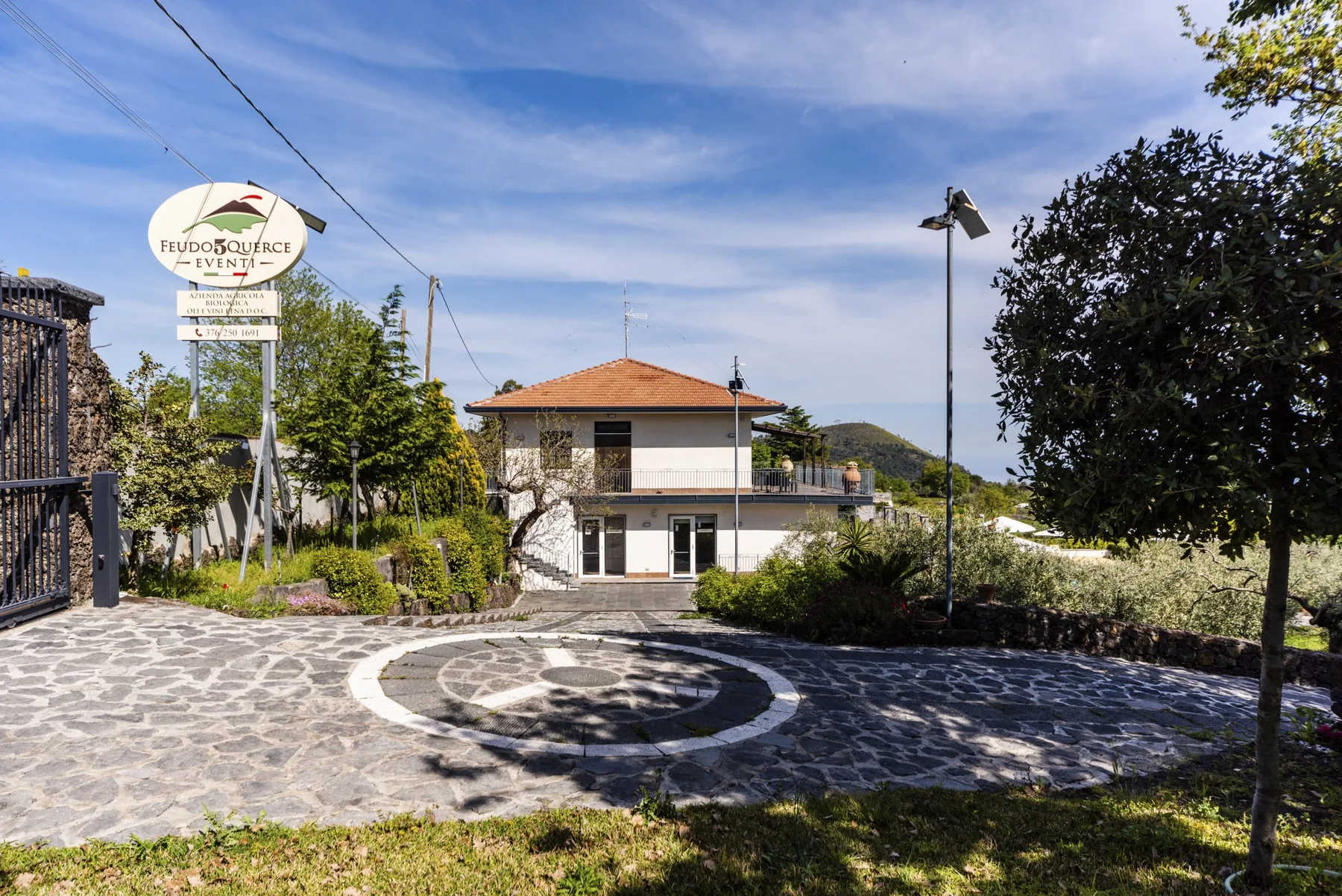 Un edificio de dos plantas se encuentra junto a una entrada pavimentada y jardines.