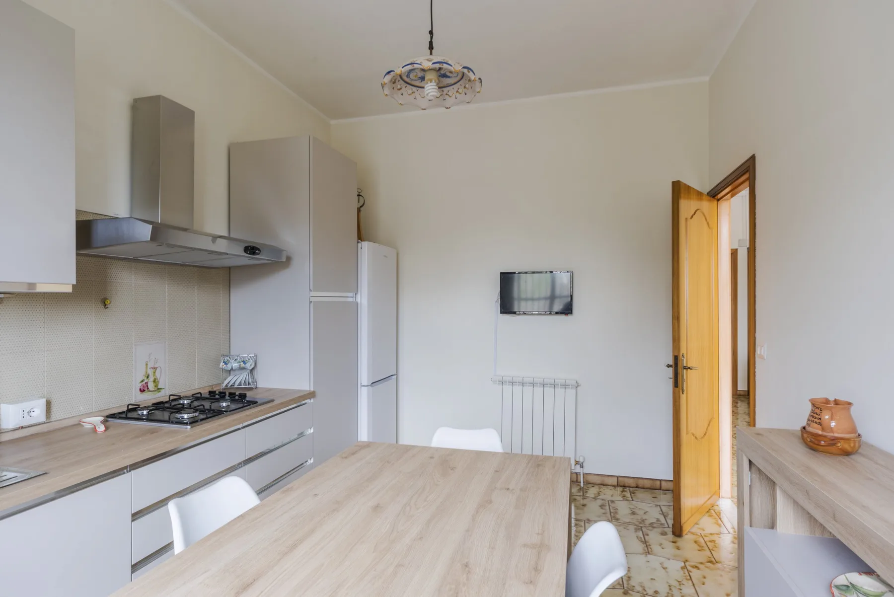 A kitchen and dining area with a table, cooking range, and open doorway.