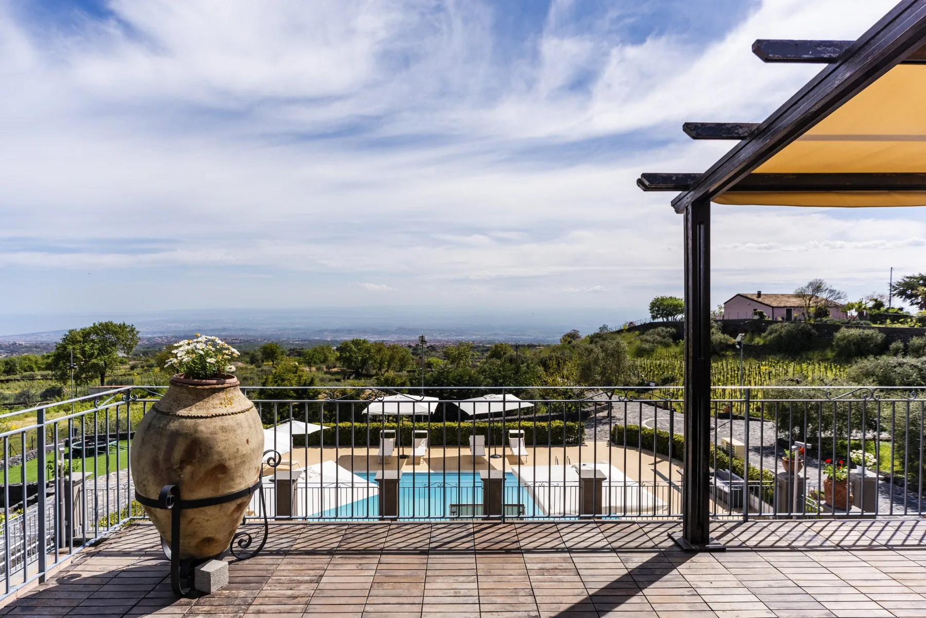 Una piscina al aire libre y una terraza ofrecen vistas de un amplio paisaje bajo un cielo parcialmente nublado.