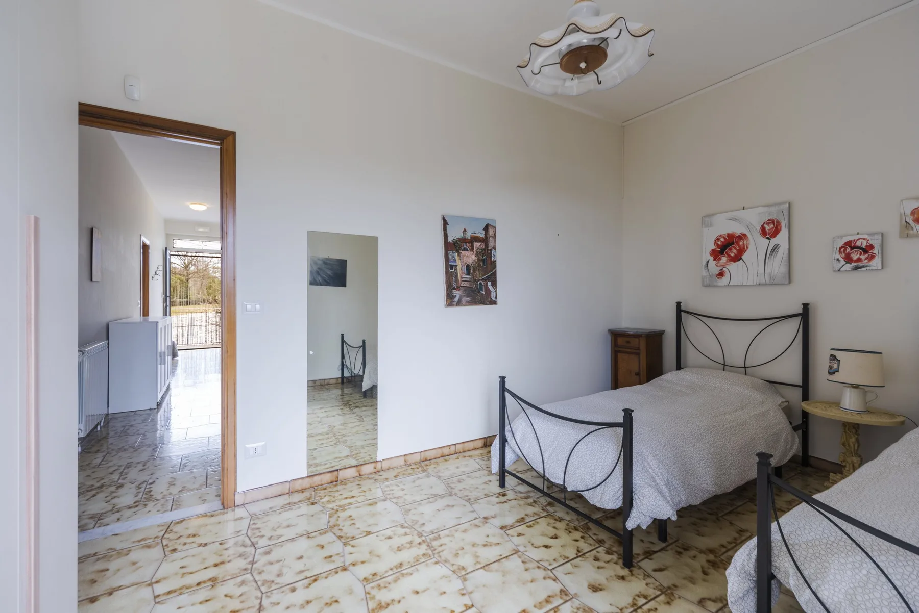 Un dormitorio con dos camas, cabeceros metálicos y suelo de baldosas estampadas.