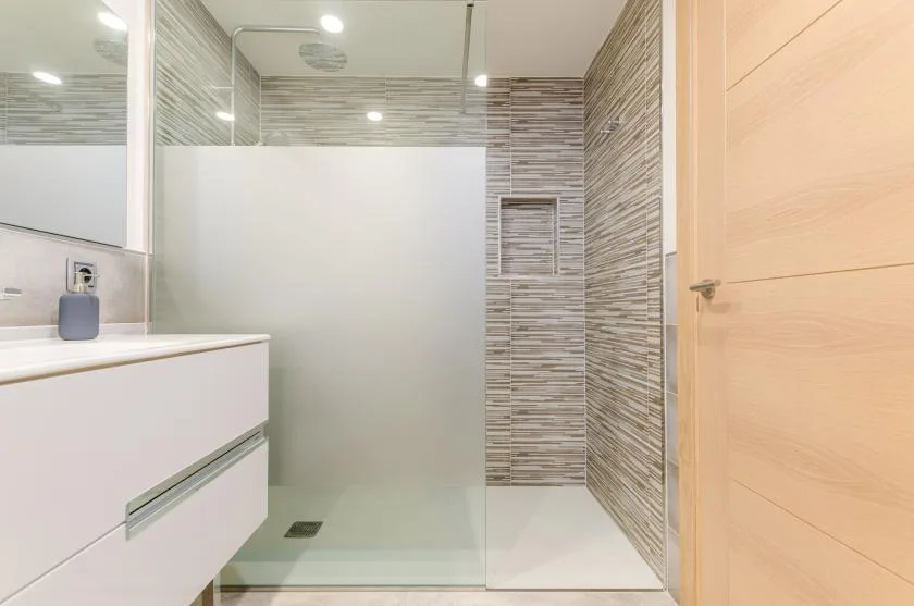 A modern bathroom with a glass shower and a white vanity.