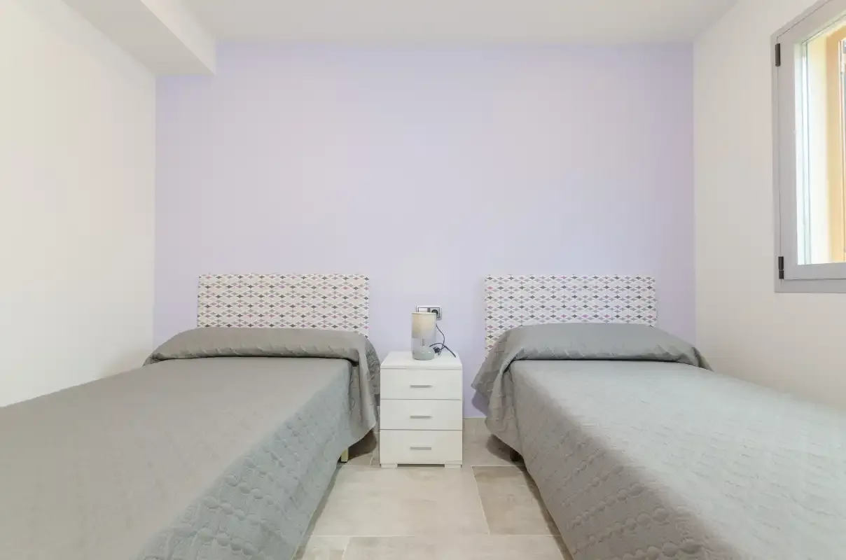 A bedroom with two single beds and a small nightstand between them.