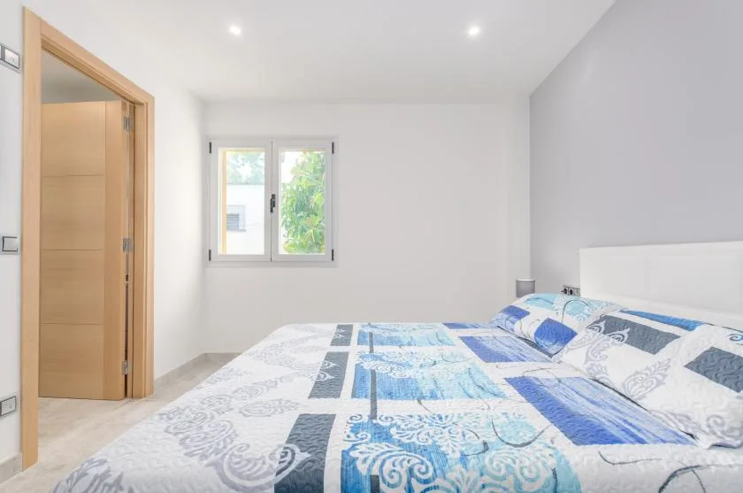 A bright bedroom with a bed covered in blue-and-white patterned bedding.