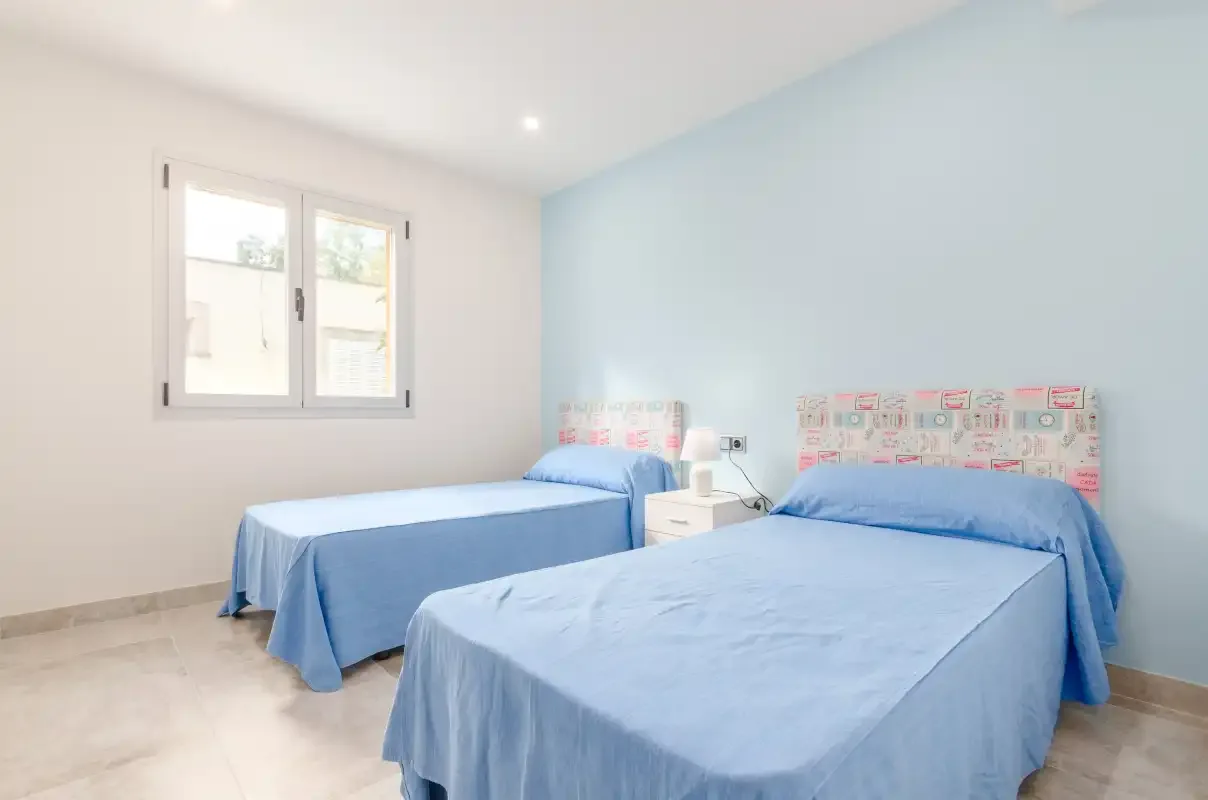 A bedroom with two beds covered in blue bedding.