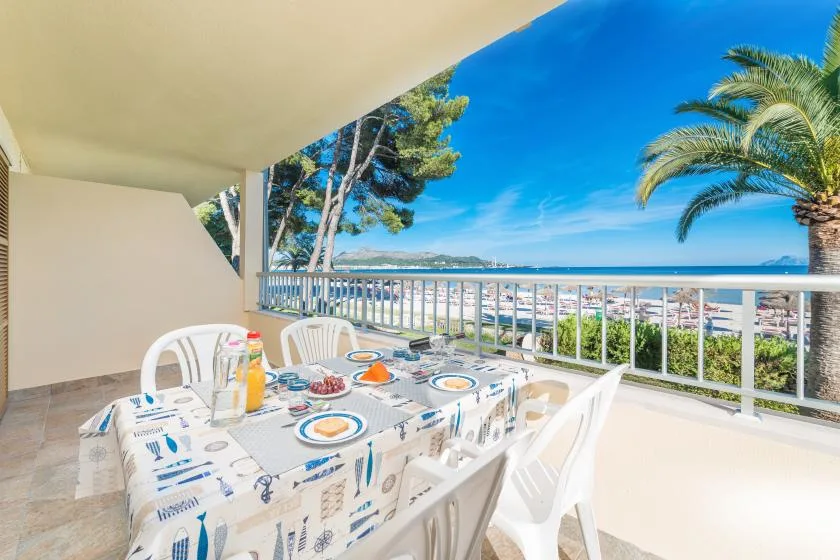 Una zona de comedor en una terraza cubierta da al mar, con mesa y asientos al aire libre.