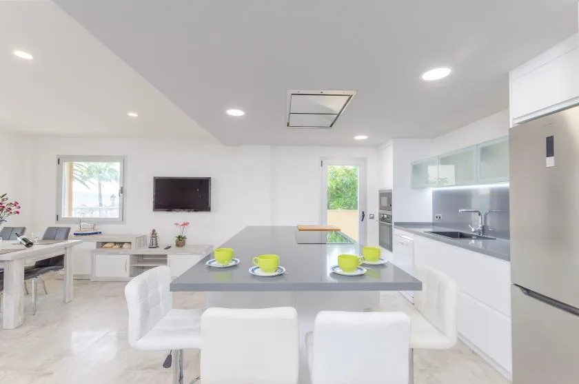 A bright kitchen and dining area with a central island and white seating.