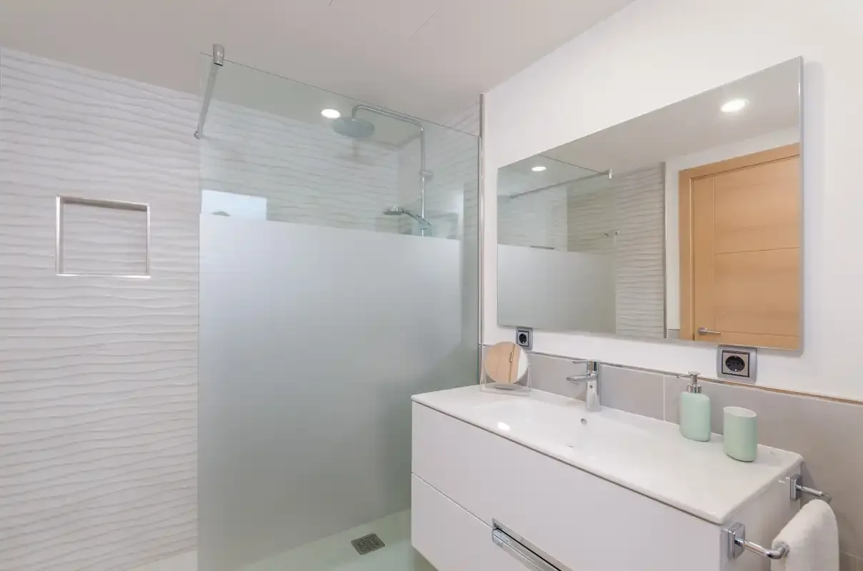 A bright bathroom with a wide sink counter and a glass shower.