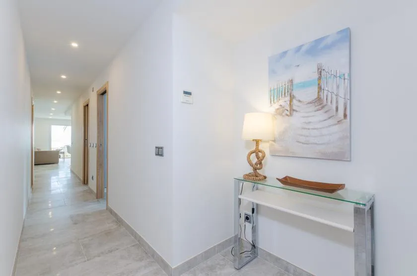 A bright hallway with a console table, lamp, and beach-themed wall art.