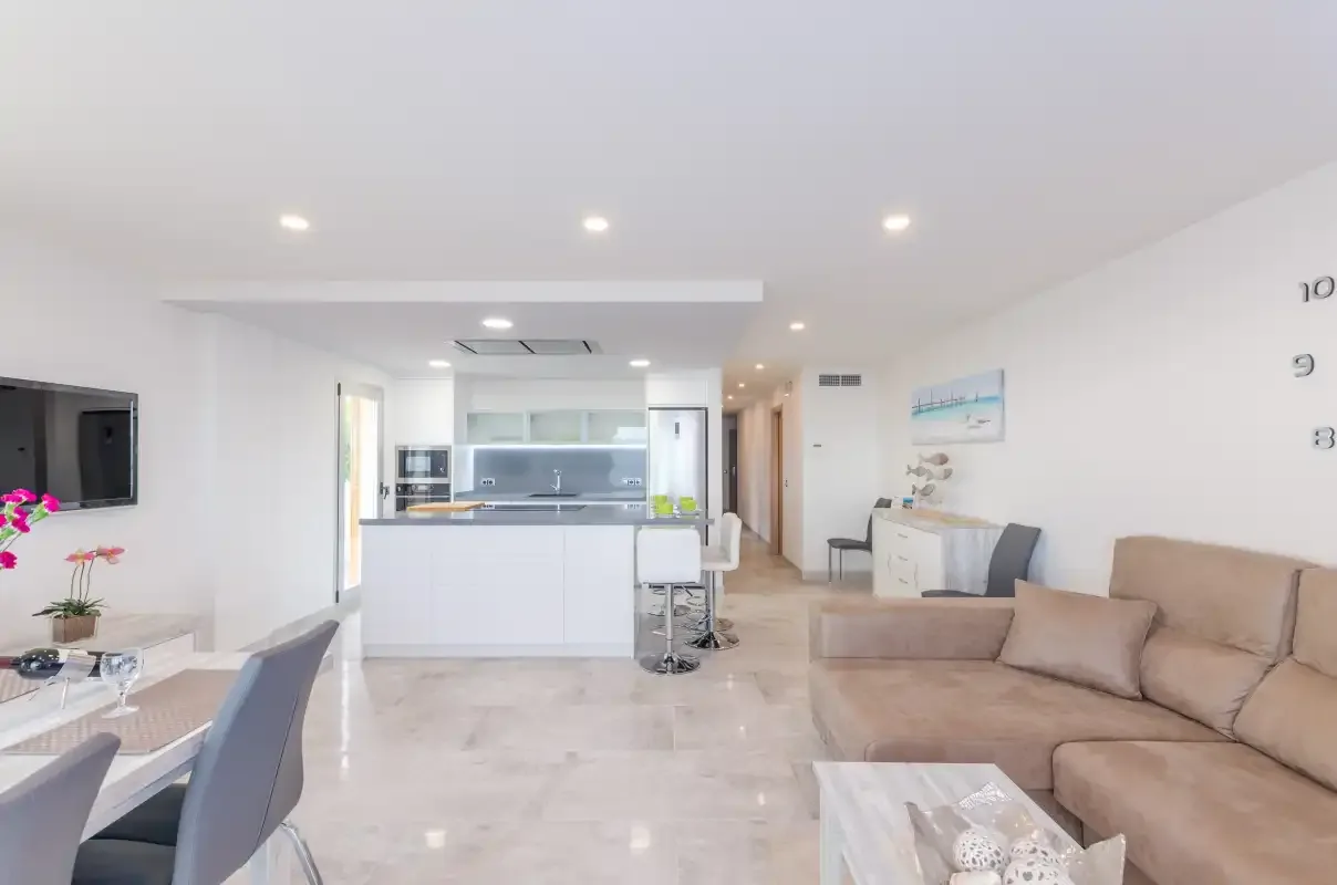 A bright open-plan living room with a kitchen, dining area, and seating.