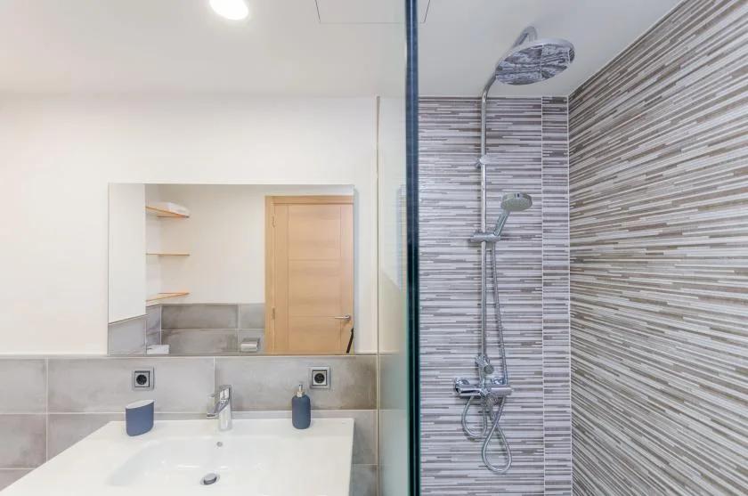 A bathroom with a sink and a wall-mounted shower.