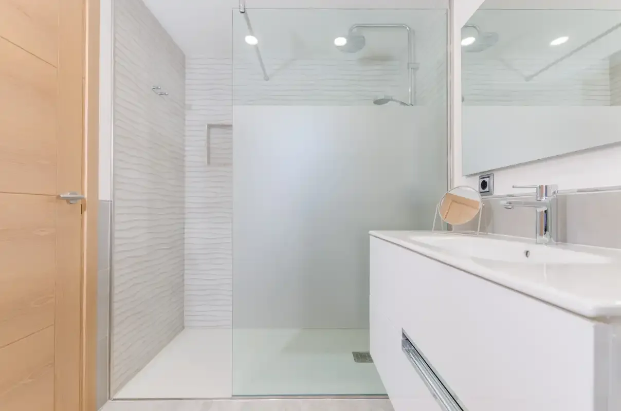 A bright bathroom with a glass shower and a white vanity.